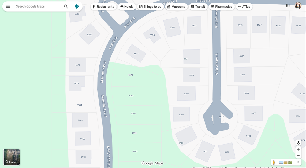 Screenshot of google maps. The map doesn't have any sidewalk mapped, the road is mapped a little weird in some areas, there's house footprints missing, all the house footprints are just squares, and there's a street address mapped in a place where there's no building